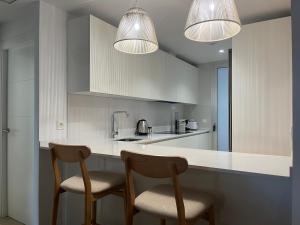 zwei Stühle an einer Küchentheke mit zwei Leuchten in der Unterkunft HOLY SEA Playa Granada Golf & Costa Tropical - Mar de Fabiola in Motril