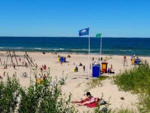 a group of people on a beach with the ocean at Cozy apartment in Ventspils