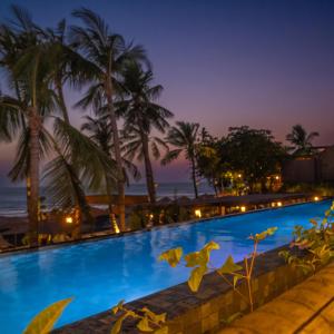 a pool with palm trees and the ocean at night at Apenunga Eco Hotel in Jericoacoara +17 photos