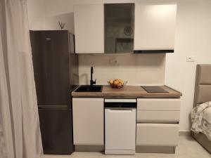 a kitchen with white cabinets and a black refrigerator at Dream - sea view apartment in Pučišća
