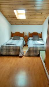 two beds in a room with a wooden ceiling at La casa del Amo , Trasmoz Y Moncayo in Trasmoz