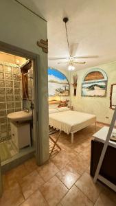 a room with a bed and a bathroom with a painting at B&B Sa Bèrtula in La Maddalena