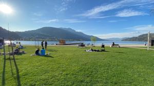 a group of people sitting on the grass near a lake at LAC Holiday Apartment in Calceranica al Lago