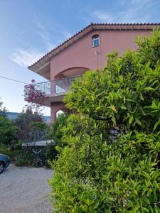 a pink house with a balcony and some bushes at Homely Escape in Chios