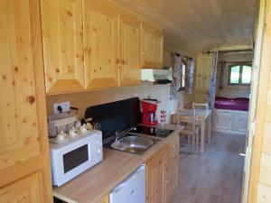 a kitchen with wooden cabinets and a sink and a stove at les roulottes des marquets in Bourthes