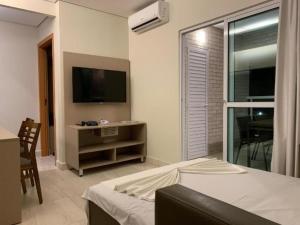 a bedroom with a bed and a tv and a window at Salinas Park Resort in Salinópolis