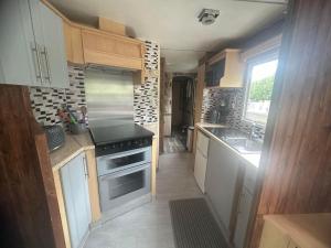 a small kitchen with a stove and a sink at Chantelle & Ashleys Caravan Getaway in Chapel Saint Leonards