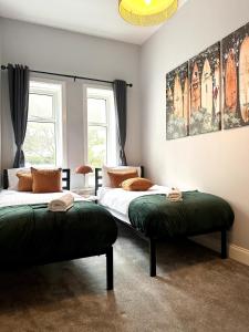 a bedroom with two beds with green cushions at The Bournemouth Haven - Brought to you by Coastline Retreats - Grand 2 bedroom luxury apartment - 3 mins walk to beach - Superfast Wifi - Sleeps 6 in Bournemouth