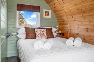 een slaapkamer met een wit bed met een raam bij The Pods at 7 Black Crofts in Oban