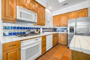 een keuken met houten kasten en witte apparatuur bij SV104 Spacious Single Story 1 Bedroom Spa Villa in La Quinta