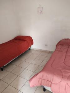 Dos camas en una habitación con una manta roja. en Depto Civora 4, en Villa Regina