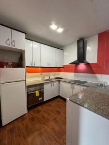a kitchen with white cabinets and a red wall at Mabel in San Javier +13 photos