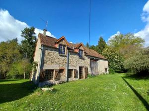 an old stone house on a grass field at Gîtes du breuil in Clugnat