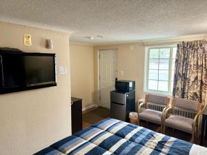 a hotel room with a bed and a flat screen tv at Gratiot View Motel in Saginaw