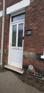 eine weiße Tür an der Seite eines Backsteingebäudes in der Unterkunft Simple, cosy and comfortable 3 beds in Kings Lynn
