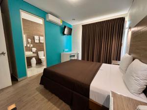 a hotel room with a large bed and a bathroom at Hotel Guivá Aeropuerto in Oaxaca City