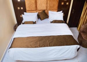 a bedroom with a large bed with white sheets at Darminah Hotel in Akure