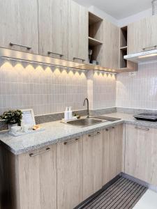 a kitchen with wooden cabinets and a sink at Cozy Staycation Studio in Iloilo by Alfasuite Iloilo in Iloilo City +7 photos