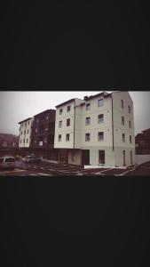 a large white building in a parking lot at Apartman Beograd Mir i Komfor in Belgrade
