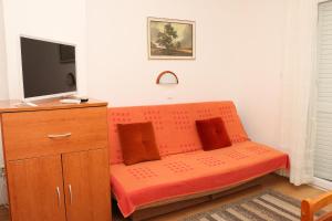 - un canapé orange dans une pièce avec une télévision dans l'établissement Apartments and rooms by the sea Kukljica, Ugljan - 24327, à Kukljica