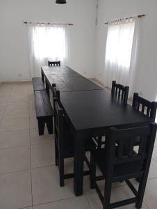 un tavolo da pranzo nero con sedie e finestre di El Quincho de Ampi a Chascomús