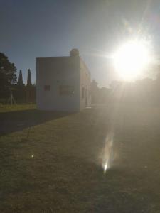 un edificio con il sole che splende dietro di El Quincho de Ampi a Chascomús Altre 2 foto