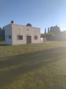 un edificio bianco in un campo vicino a un campo di El Quincho de Ampi a Chascomús