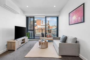 a living room with a couch and a tv at Modern 1b Apt Near Swinburne University in Melbourne