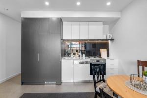 a kitchen with white cabinets and a table and a table and a table at Modern 1b Apt Near Swinburne University in Melbourne