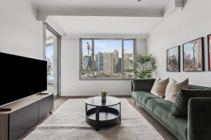 a living room with a green couch and a tv at Darling Harbour Views 2BR 2Bath, Pool, Parking, Spa & Gym in Sydney