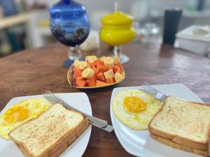 a table with two plates of eggs and toast and fruit at Lanina homestay in Ipi