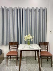 a table with two chairs and a vase with flowers at HG House in Da Nang