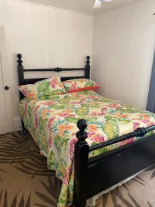 a bed with a floral comforter and two pillows at This is it! Dreamy Beach, Stunning Views, Awesome Location in Kilauea