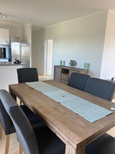 a wooden table with chairs in a kitchen at Amaroo holiday home in Kingscote