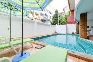 a swimming pool with chairs and an umbrella at Sun and beach hotel in Pattaya South