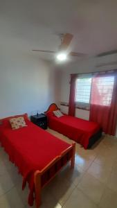 two beds in a room with red sheets at M&P alquiler por día in La Rioja +7 photos