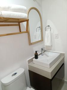a bathroom with a sink and a toilet and a mirror at Enamórate in Mazatlán