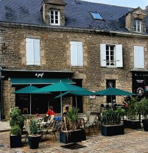 ein Café im Freien mit Tischen, Stühlen und Sonnenschirmen in der Unterkunft Les remparts de Guerande in La Celle-sous-Gouzon