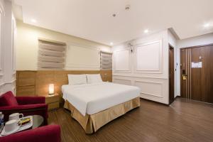 a bedroom with a white bed and a red chair at A25 Hotel - 21 Le Duc Tho in Hanoi