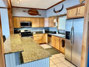a kitchen with wooden cabinets and a stainless steel refrigerator at Downtown Wasilla Lakefront Home in Wasilla