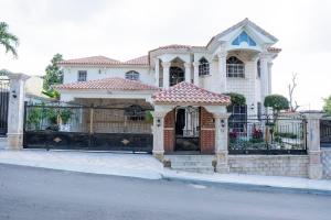 a white house with a gate and a fence at Villa La Dueña - Vista Hermosa Luxury Retreat, 5BR Villa with Pool, Swim-Up Bar, Jacuzzi, Chef's Kitchen, Fast Wi-Fi, Full AC, EV Charger and Solar Power, Ideal for Families & Groups in Cancino
