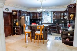 a kitchen with wooden cabinets and a island with bar stools at Villa La Dueña - Vista Hermosa Luxury Retreat, 5BR Villa with Pool, Swim-Up Bar, Jacuzzi, Chef's Kitchen, Fast Wi-Fi, Full AC, EV Charger and Solar Power, Ideal for Families & Groups in Cancino