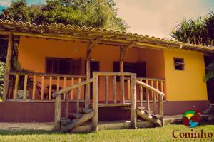 una casa amarilla con un porche de madera delante de ella en Hotel Fazenda Coninho en Inhaúma