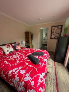 a bedroom with a red bed with two black objects on it at Blackbird Cottage Tiny Home in Thirlmere