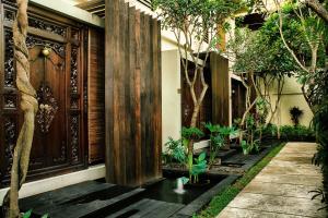 a house with a courtyard with trees and a wooden door at Sagara Villas and Suites Sanur in Sanur