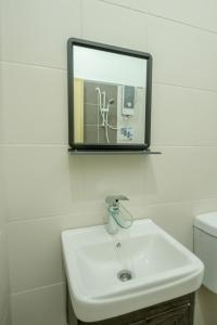 ein Badezimmer mit einem weißen Waschbecken und einem Spiegel in der Unterkunft Bermaley Bukit Keluang, Besut in Kampung Raja