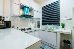 eine Küche mit weißen Schränken und einer schwarzen Mikrowelle in der Unterkunft Bermaley Bukit Keluang, Besut in Kampung Raja + 6 Fotos