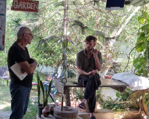 a man sitting on a table talking to another man at Dream Vision Guest House in Diu