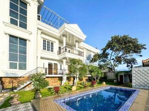 a large house with a swimming pool in front of it at Villa putih 10 kamar in Tlekung