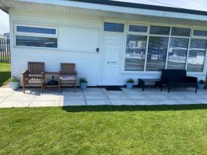 two chairs and a table in front of a house at Chalet 65 in Chapel Saint Leonards +7 photos